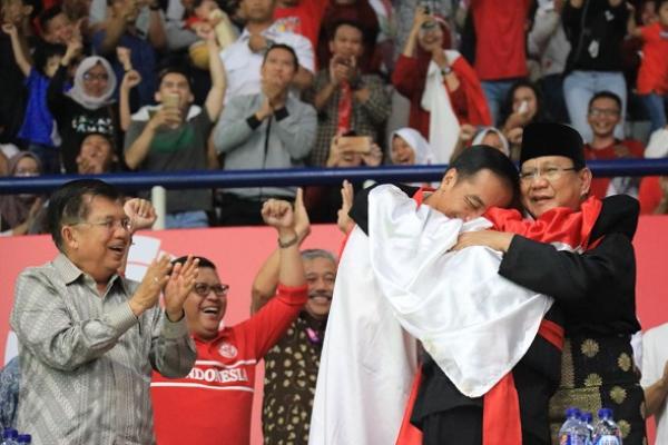 Presiden Jokowi dengan Prabowo Subianto berpelukan saat merayakan kemenangan atlet Pencak Silat Hanifan Yudani Kusumah, dalam pertandingan Asian Games 2018.